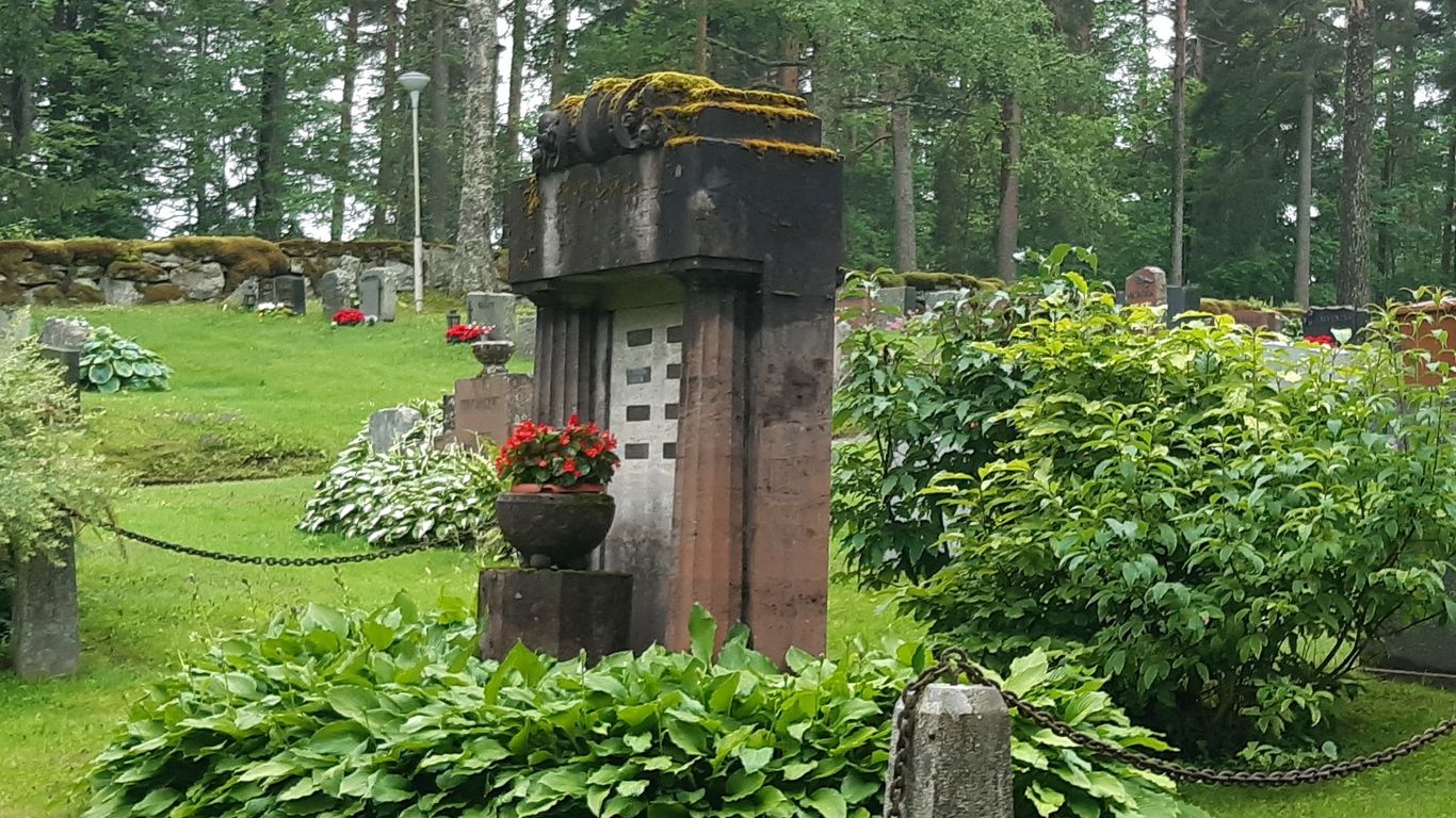 Vehreä hautausmaanäkymä. Keskellä vanha sammaloitu