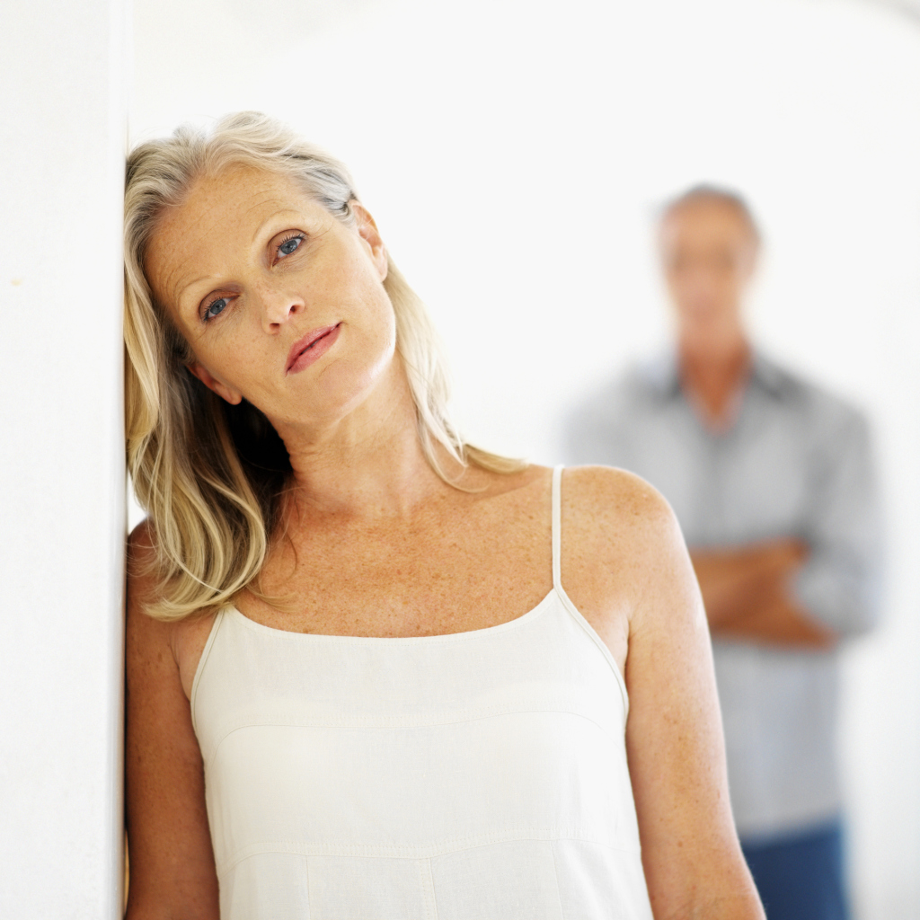 Frau an der Wand lehnend, Mann verschwommen im Hintergrung Frau an der Wand lehnend, Mann verschwommen im Hintergrung