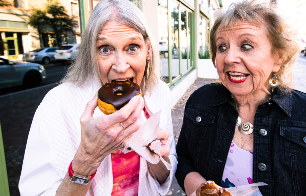 Zwei ältere Frauen essen Donuts Zwei ältere Frauen essen Donuts