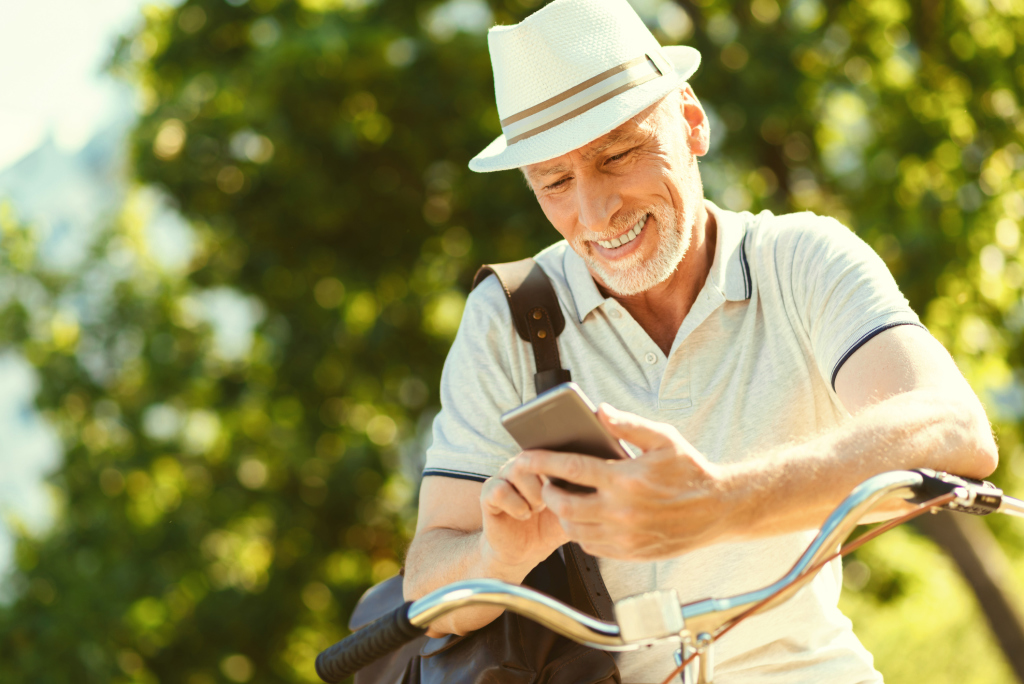 Senior beim Radfahren mit Smartphone Senior beim Radfahren mit Smartphone