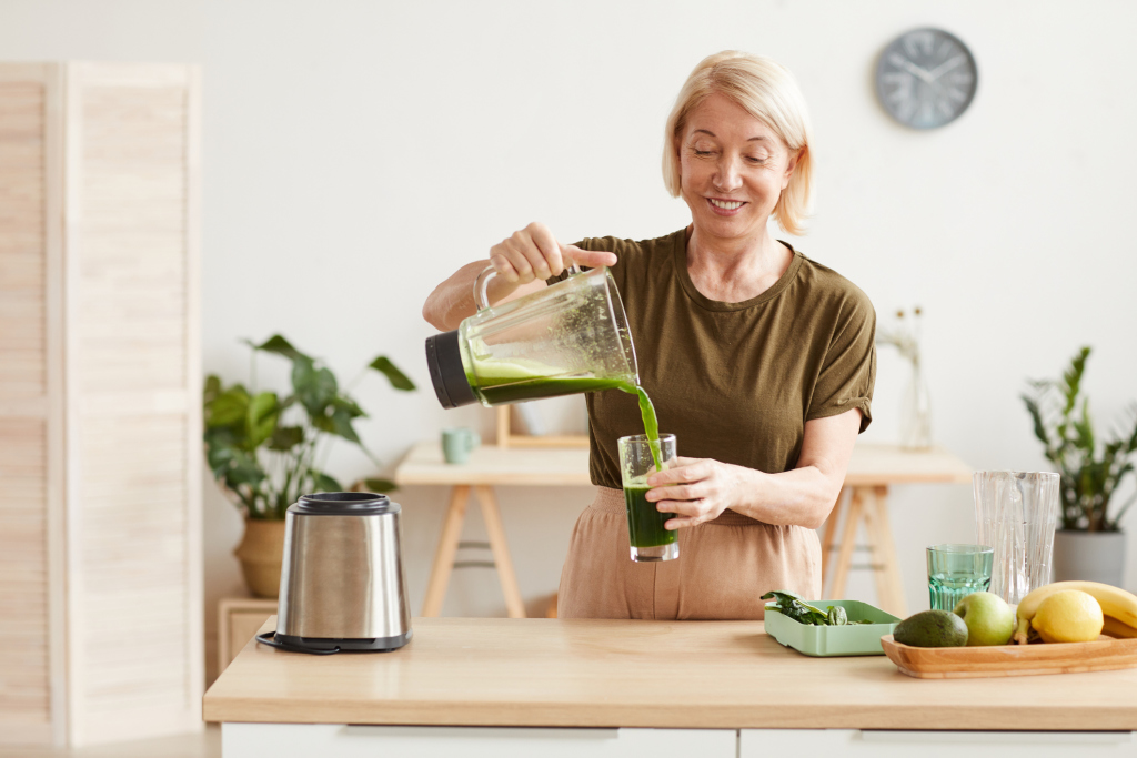Frau gießt grünen Smoothie in ein Glas Frau gießt grünen Smoothie in ein Glas