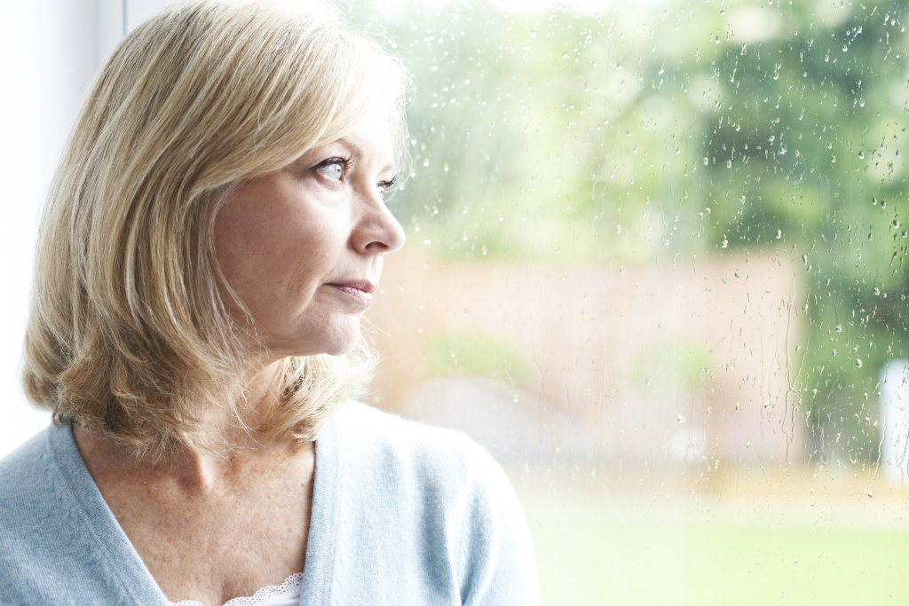 Frau schaut traurig aus dem Fenster Frau schaut traurig aus dem Fenster