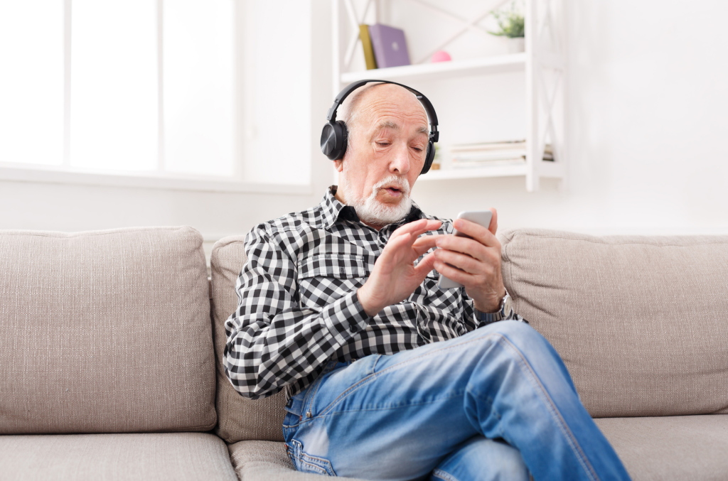 Mann mit Kopfhörern und Handy auf dem Sofa Mann mit Kopfhörern und Handy auf dem Sofa