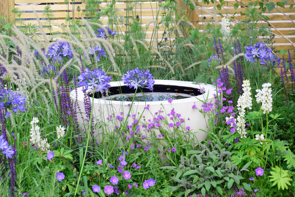 moderner Wasserbrunnen mit lila Blumen moderner Wasserbrunnen mit lila Blumen