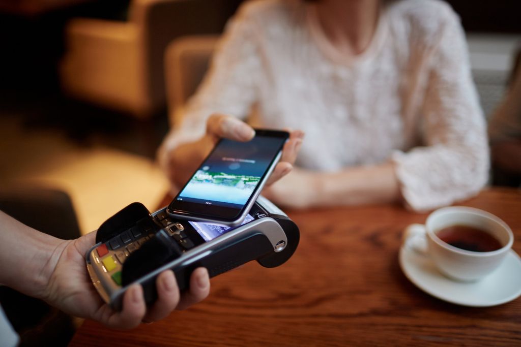 Frau bezahlt mit dem Handy Frau bezahlt mit dem Handy