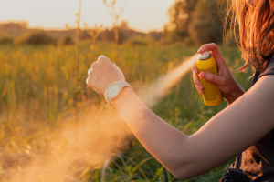 Frau sprüht Insektenschutzspray auf den Arm Frau sprüht Insektenschutzspray auf den Arm