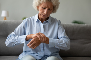 Seniorin massiert Handgelenk Seniorin massiert Handgelenk
