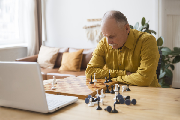 Senior spielt Schach gegen Gegner per Videochat Senior spielt Schach gegen Gegner per Videochat