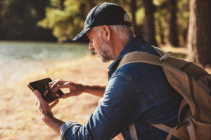 Senior mit Handy beim Wandern Senior mit Handy beim Wandern