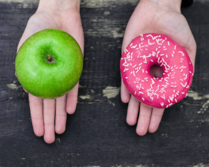 Ein Apfel und ein Donut jeweils auf einer Hand Ein Apfel und ein Donut jeweils auf einer Hand