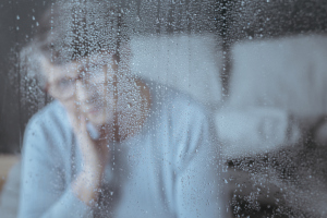 Traurige Frau vor verregnetem Fenster Traurige Frau vor verregnetem Fenster