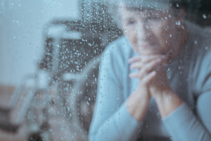 Frau schaut traurig aus verregnetem Fenster Frau schaut traurig aus verregnetem Fenster