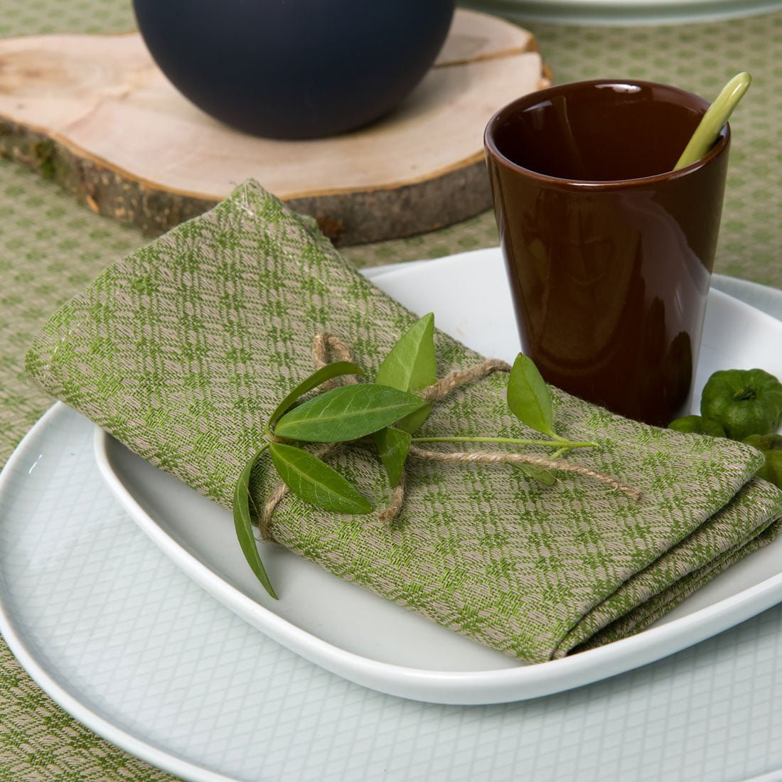 Lininė stalo servetėle žalios spalvos si pilku raštu.