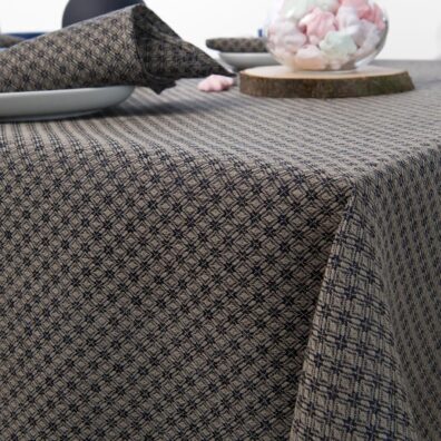 Pilkos si juodais rombais lininės staltiesės kampo vaizdas.