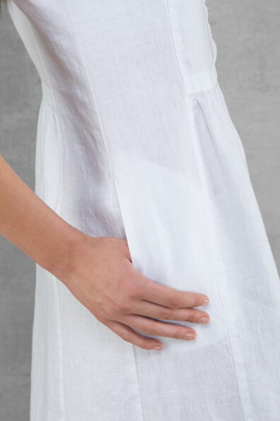 Ryškiai balta lininė suknelė su kišenėmis.