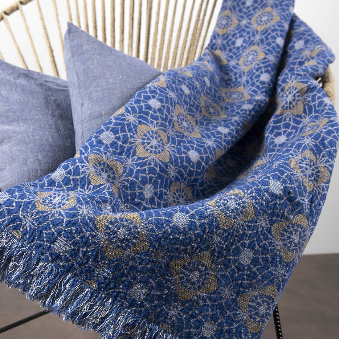 Minšktas pledas iš lino, mėlynos spalvos, su geltonu raštu.