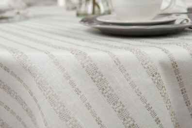 Apvali ovali puslininė balta staltiesė su pilkomis tautinių motyvų juostelėmis.