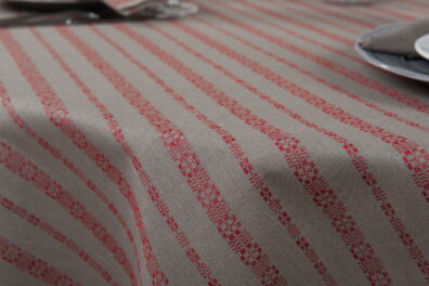 Apvali (ovali) puslininė pilka staltiesė su raudonomis raštuotomis juostelėmis.