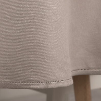 Apvali (ovali) pilkšvai rausva staltiesė su mereškuota eilute aplink.