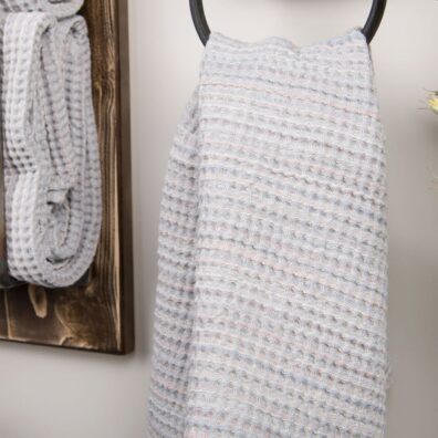 Šviesiai pilkas vonios rankšluostis su spalvotomis juostelėmis.