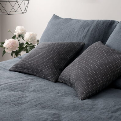 Lininė patalynė melsvai pilka: antklodės, pagalvės užvalkalas, dekoratyvinės pagalvėlės užvalkaliukas tamsiai pilkas baltai taškuotas.