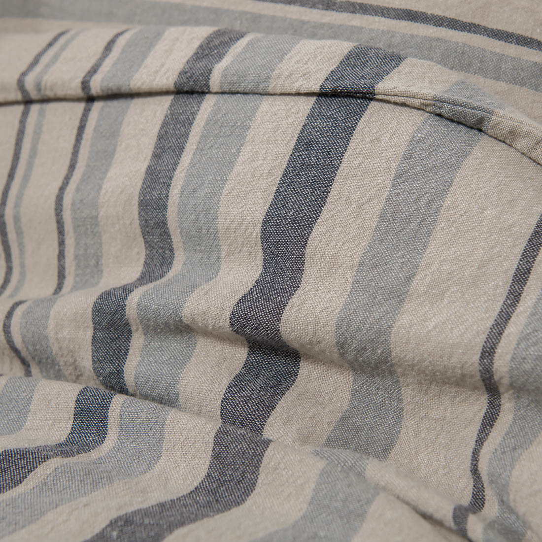 Lininė patalynė pilkai juodai dryžuota, jos audinys iš arti.