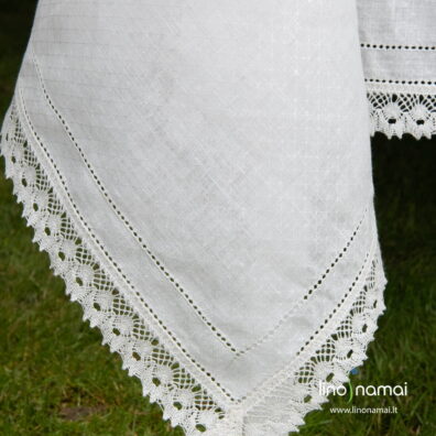 Raštuotos baltos lininės staltiesės kraštinės puoštos nėriniais ir dviem mereškuotomis eilutėmis