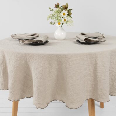 Lininė apvali natūralios spalvos staltiesė su tamsiai pilka tankia dekoratyvine siūle aplink ir derančios servetėlės