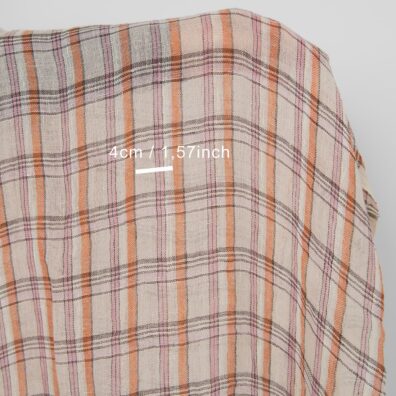 Lininis audinys įvairiaspalviais langeliais smėlio spalvos fone permatomas skalbtas