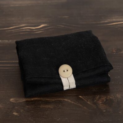 Lininis juodas krepšys sagos ir kilputės pagalba susilanksto į mažą paketėlį.