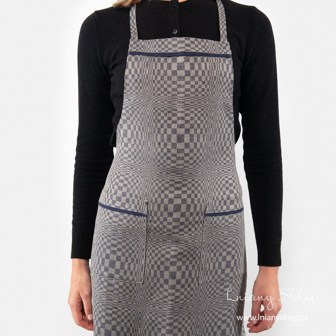 Kieszenie i pod szyją fartuch zdobi granatowa lamówka.