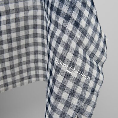 Prześwitująca tkanina mlecznobiałą-granatowoczarną krateczkę.