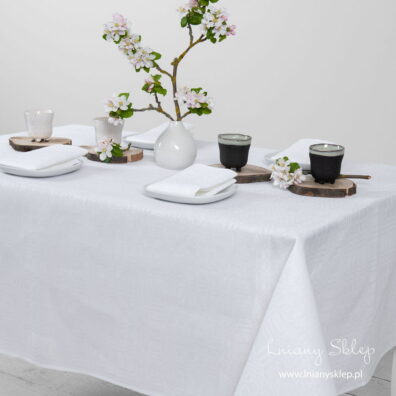 Biały lniany obrus w kratkę. Gładko podwinięty brzeg.