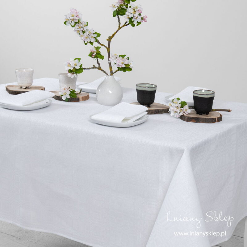 Biały lniany obrus w kratkę. Gładko podwinięty brzeg.