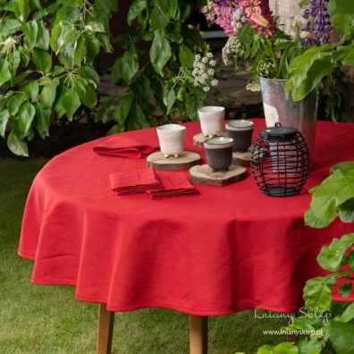 Czerwony okrągły (owalny) obrus wykończony mereżką.