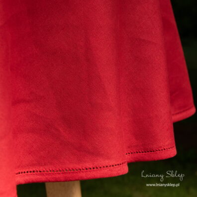 Czerwony okrągły (owalny) obrus wykończony mereżką.