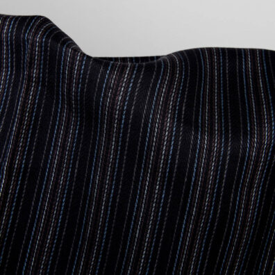 Czarny len wytkany splotem jodełkowym w biegnące pionowo, ciemne i kolorowe paski: jasnoszare, ciemnoszare, brązowe i granatowe.