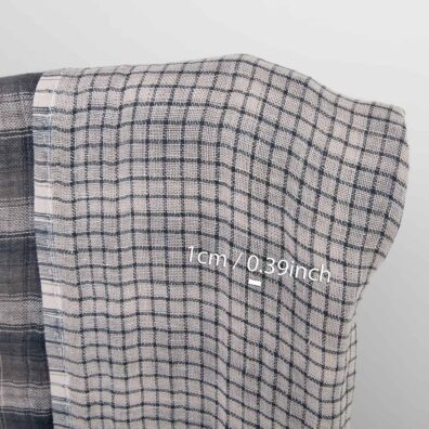 Jedna strona tkaniny - w dość dużą kratkę wytkaną z przędzy o różnych szarych odcieniach, druga - w drobną krateczkę z szarej i ciemnej szaro - granatowej przędzy.