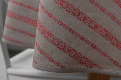 Okrągły lub owalny obrus lniany w czerwone ornamenty.