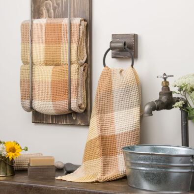 Komplet dwu brązowych ręczników kąpielowych przewiązanych lnianą wstążeczką.