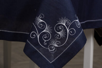 Rogi obrusu zdobi haft, brzegi - biała mereżka.