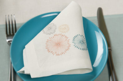 Biała, pastelowo haftowana serwetka lniana.