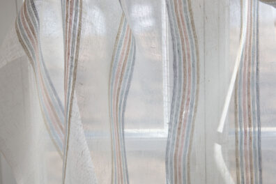 Biała tkanina w zielonkawe, różowe, piaskowe, niebieskawe i żółtawe paski.