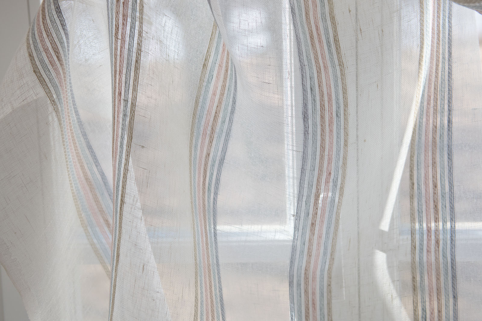 Biała tkanina w zielonkawe, różowe, piaskowe, niebieskawe i żółtawe paski.