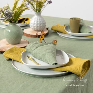 Obrus zielona oliwka z żółtymi i zielonymi serwetkami.