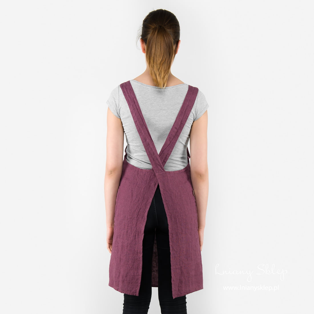 Lniany wiśniowy fartuch. Szelki skrzyżowane na plecach.