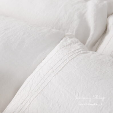 Mlecznobiała pościel ozdobiona mereżką i zaszewkami.