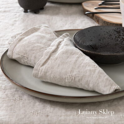 Szara serwetka wytkana na gładkim tle w ażurowe "okienka".