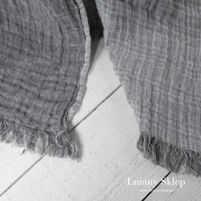 Szary pled z frędzelkami.