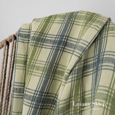 Pled z granatowej i zielonej o różnych odcieni przędzy wytkany w kratkę.